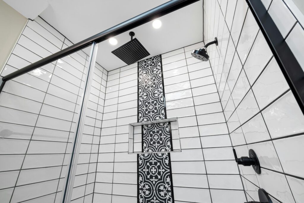 Stylish bathroom with a modern shower featuring a patterned tiled wall and black fixtures.